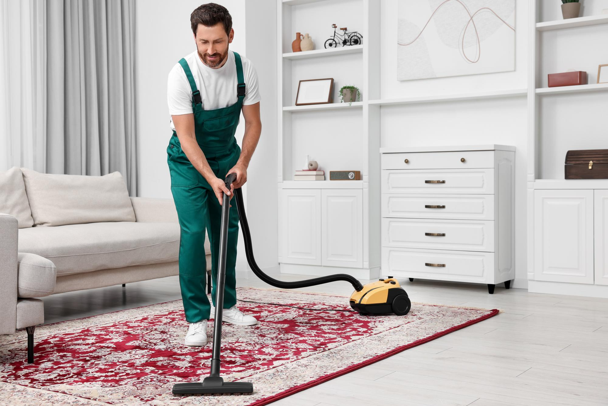 A carpet cleaner vacuuming a rug in a bright living room